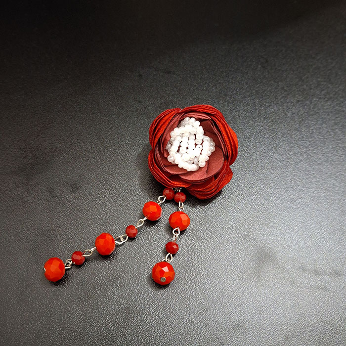 Bros bunga maroon dengan hiasan manik-manik panjang, menambah kesan anggun untuk hijabers modern 2025.