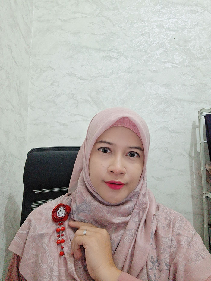 Bros hijab terbaru 2025 berbentuk bunga maroon dengan gantungan manik-manik panjang yang feminin.